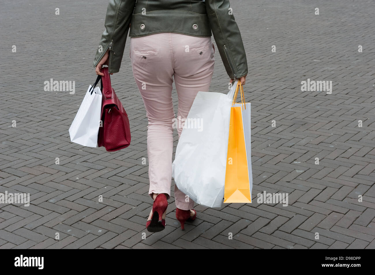 Una donna che cammina sulla strada con le borse della spesa Foto Stock