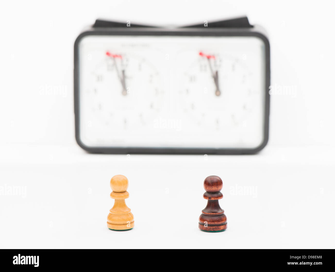 Studio shot di pezzi di scacchi bianchi e neri pedina con orologio di scacchi in background. Foto Stock