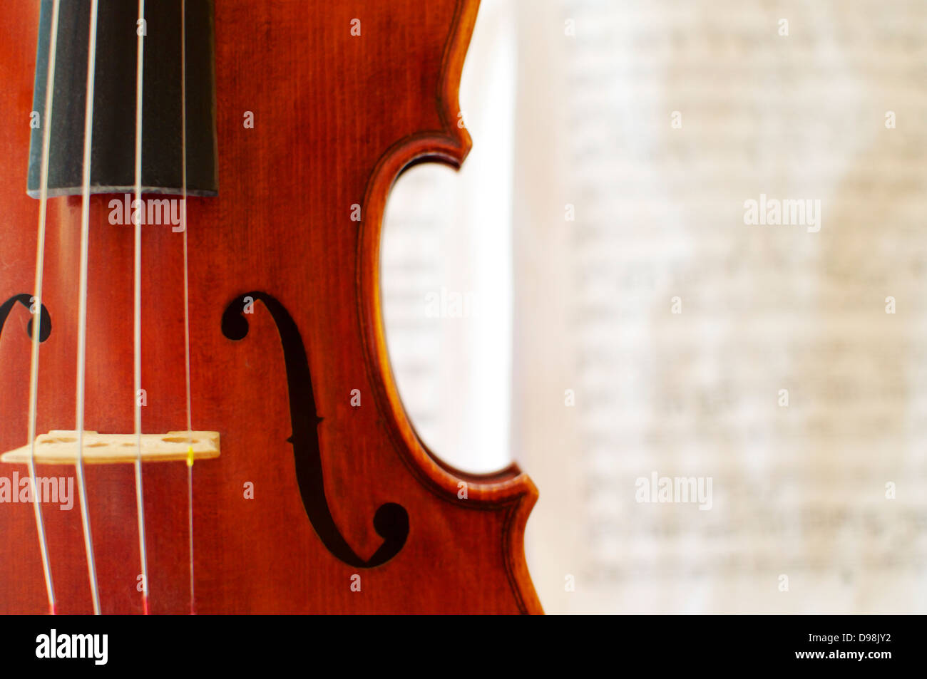 Dettaglio di un bellissimo violino con un sfocato spartito musicale in background. Foto Stock