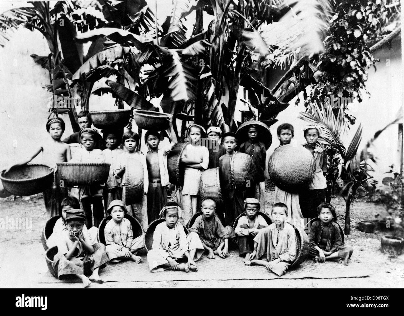 I bambini con realizzato localmente ceste poste sotto una palma, Saigon Vietnam del Sud, c1900. Saigon era la capitale e il centro commerciale del colonialismo francese in francese Indo-China. Foto Stock