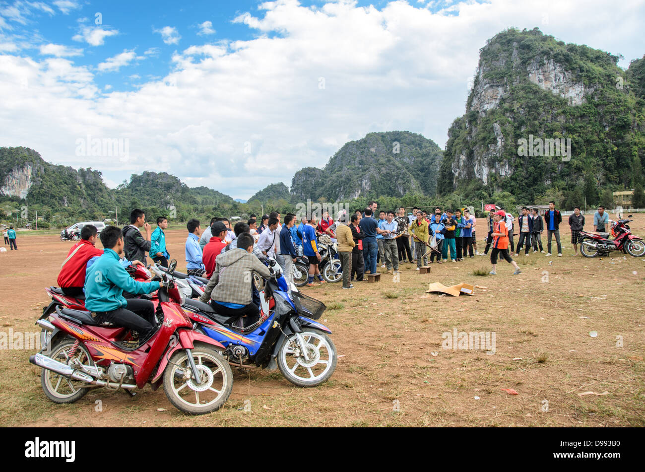 Gli spettatori del Crossbow Contest Vieng Xai Laos // VIENG XAI, Laos - gli spettatori studenteschi si allineano sui loro scooter e motociclette per assistere a una gara di balestra che si svolge su un campo di gioco sterrato nel terreno accidentato vicino a Vieng Xai nel nord-est del Laos. Il tradizionale evento sportivo attira partecipanti e spettatori dai villaggi circostanti in questa regione rurale montana. Vieng Xai, situata nella provincia di Houaphanh, è conosciuta per il suo paesaggio carsico calcareo e la rete di grotte che servirono come quartier generale per il Pathet Lao durante la seconda guerra d'Indocina. La città si trova vicino al confine con il Vietnam Foto Stock