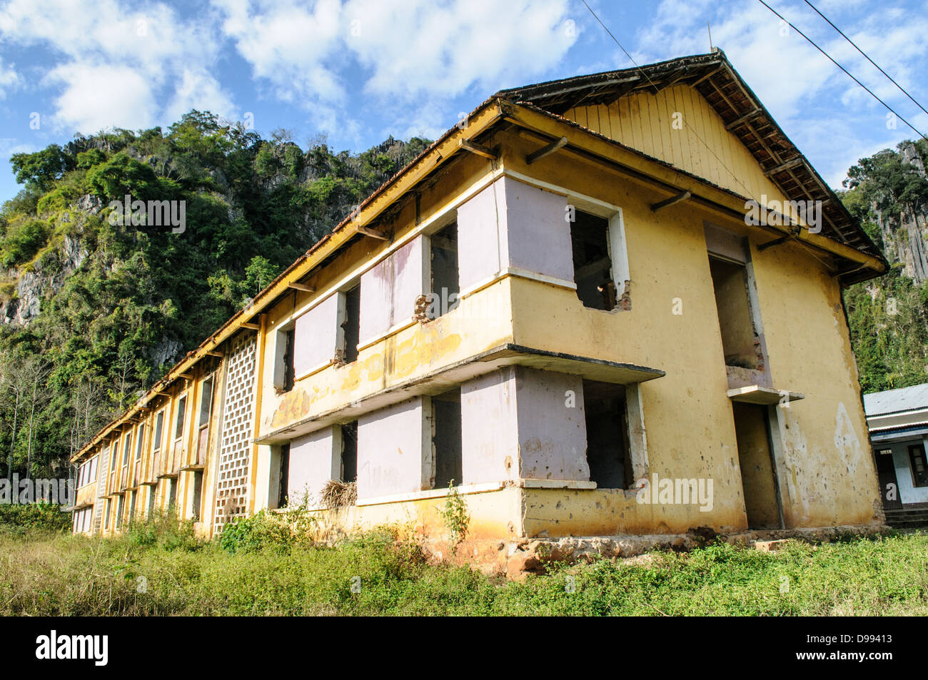 VIENG XAI, Laos — Un edificio della scuola elementare si trova all'interno del complesso delle grotte ospedaliere presso le grotte Pathet Lao a Vieng Xai, provincia di Houaphanh. Queste grotte servirono come struttura medica completa durante la guerra del Vietnam, fornendo rifugio e cure mediche ai combattenti e ai civili Pathet Lao. La rete di grotte ospitava non solo strutture mediche ma anche infrastrutture educative, dimostrando la creazione di comunità sotterranee complete durante il conflitto. Il Pathet Lao, il movimento politico comunista e l'organizzazione in Laos, usò questo vasto sistema di grotte come loro quartier generale Foto Stock