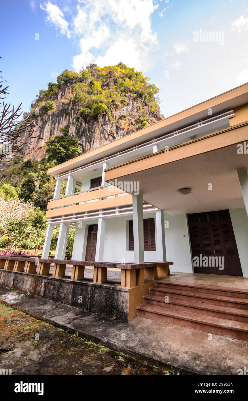 VIENG XAI, Laos - Un edificio si erge davanti alle caratteristiche formazioni calcaree che caratterizzano il complesso di grotte di Vieng Xai nel Laos nord-orientale. Le grotte di Vieng Xai servirono come quartier generale e città nascosta per le forze comuniste Pathet Lao durante la seconda guerra d'Indocina dal 1964 al 1973. La vasta rete di grotte ha fornito rifugio a un massimo di 23.000 persone, tra cui la leadership di Pathet Lao, durante il periodo di intense campagne di bombardamento degli Stati Uniti. Il sito presenta più di 480 grotte scavate nel suggestivo paesaggio carsico di pietra calcarea. Oggi, le grotte di Vieng Xai funzionano come un istore Foto Stock
