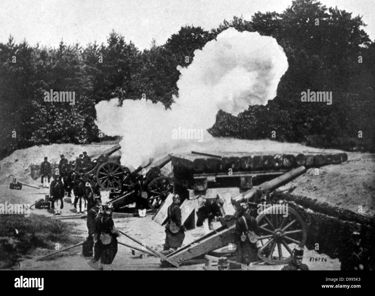 Un belga di artiglieria pesante batteria in actiion, pistole sparare da dietro uno schermo di alberi, c1914. Foto Stock