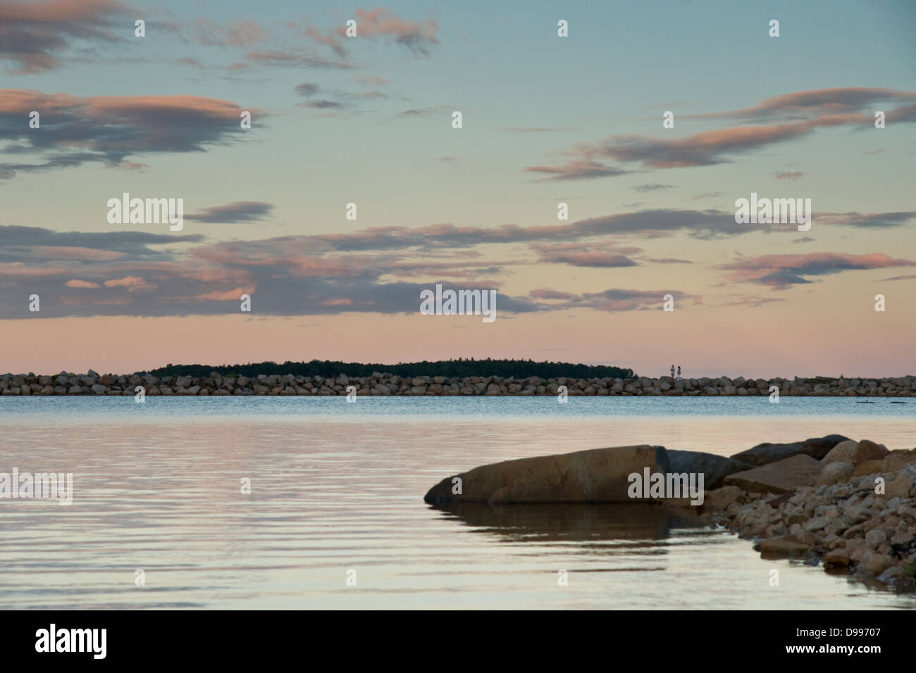 Alba su Oak Island, Nova Scotia, con due persone a piedi lungo il muro frangiflutti. Foto Stock