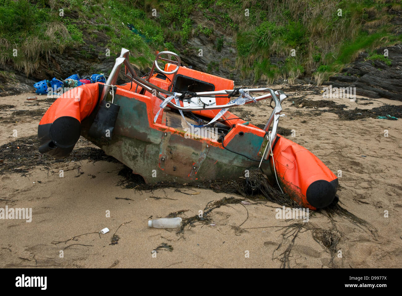 Una rotta e devastata barca rigida gonfiabile lavato fino a una spiaggia Foto Stock Una rotta e devastata barca rigida gonfiabile lavato fino a una spiaggia Foto Stock