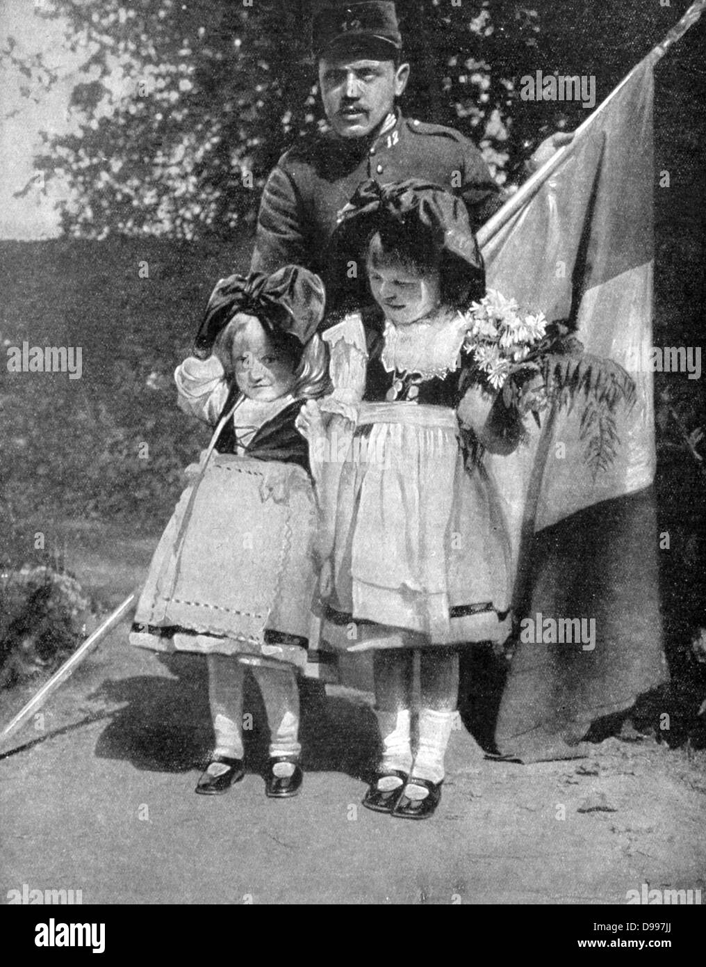 I Guerra Mondiale 1914-1918: le piccole bambine dall'Alsazia in costume regionale nella parte anteriore del soldato francese tenendo un tricoleur. Perso in Germania nel 1871, Alsazia tornò in Francia dopo la guerra. "Le Pays de France', 9 settembre 1915. Proaganda Foto Stock