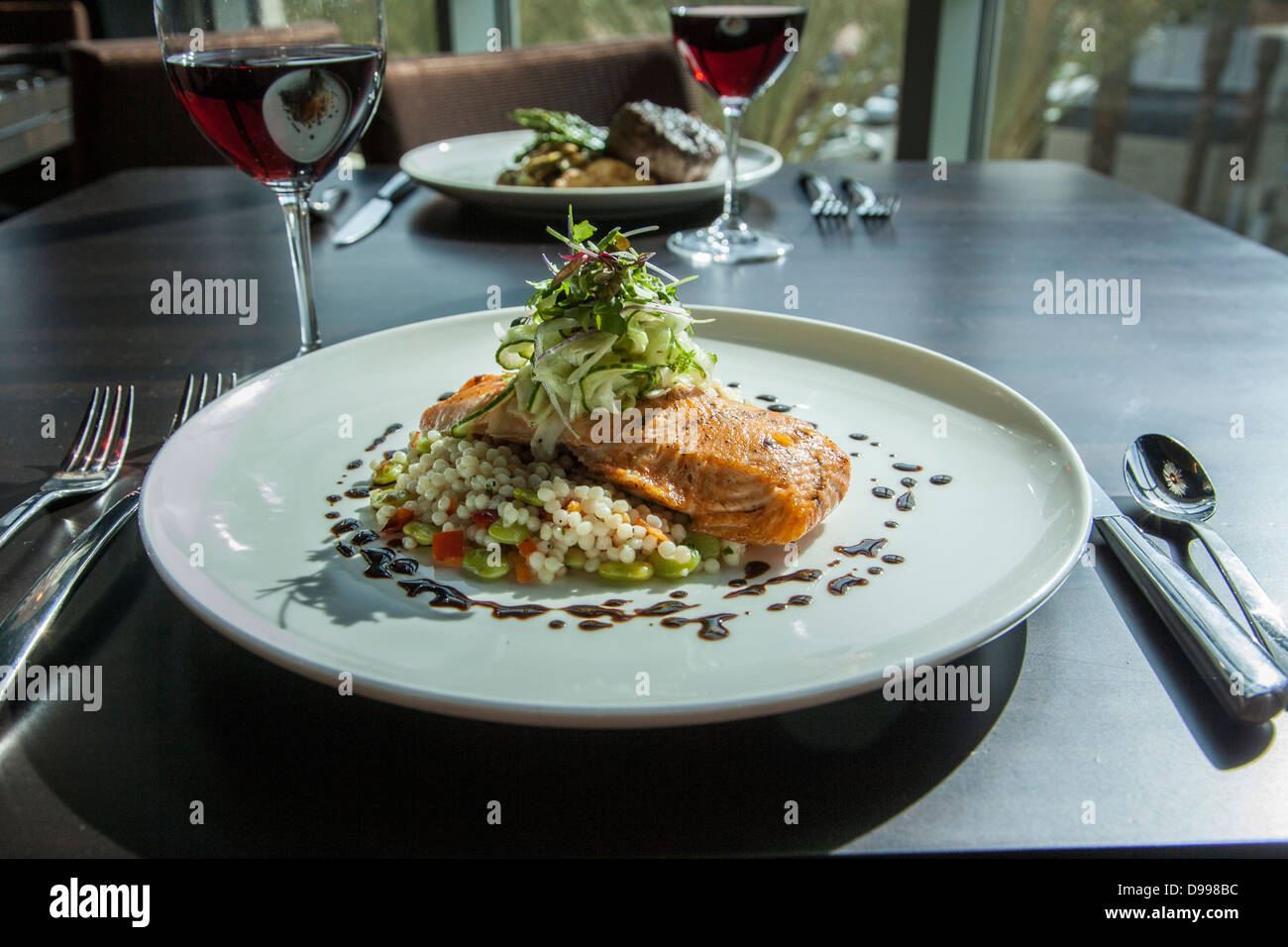 Salmone rosolata e il couscous su una piastra di cena al tavolo Foto Stock