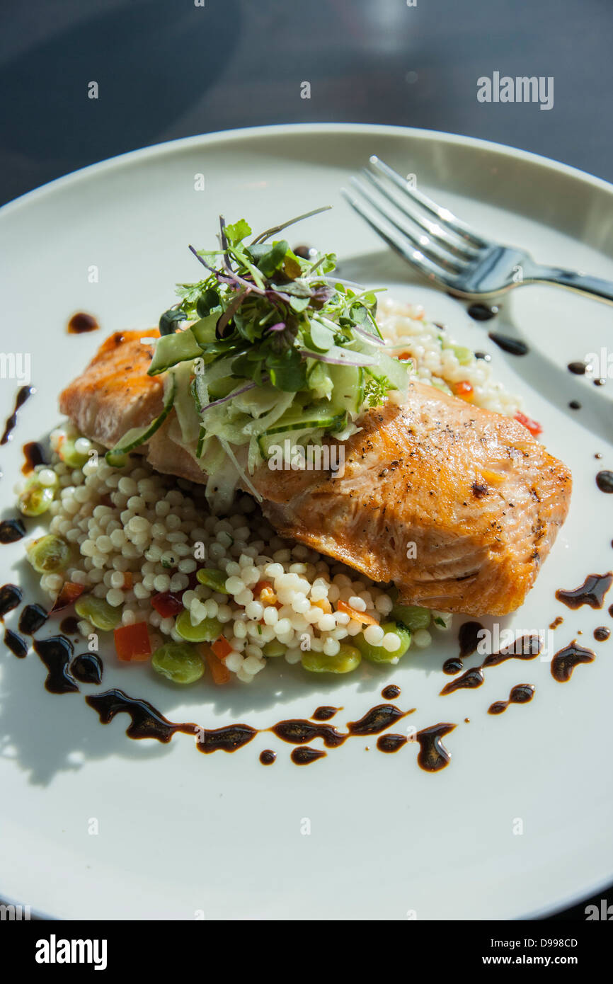 Salmone rosolata e il couscous su una piastra di cena al tavolo Foto Stock