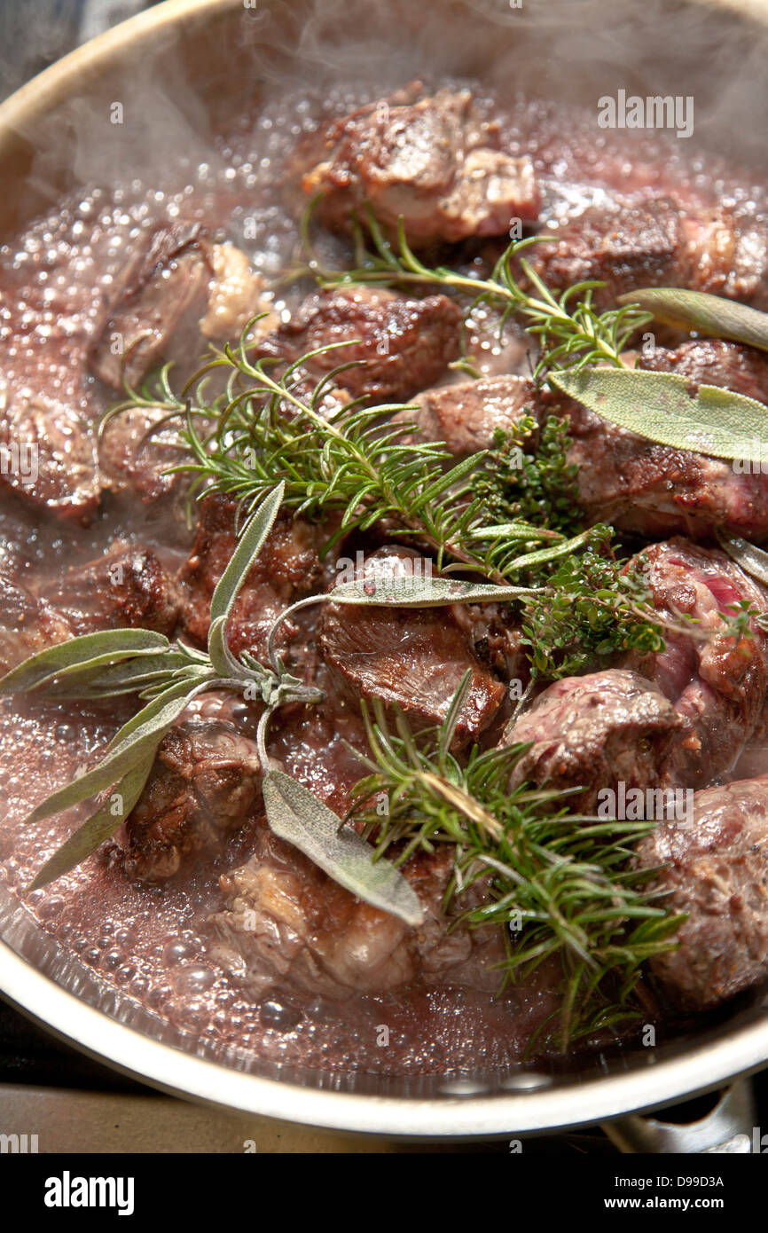 Brasati di carne in una padella con erbe fresche e vino rosso Foto Stock