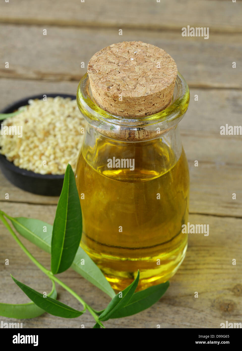 I semi di sesamo e l'olio su una tavola di legno Foto Stock