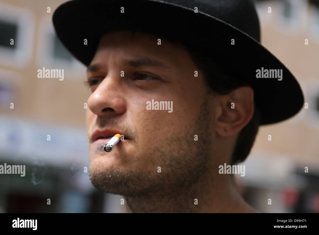 L uomo nella HAT di fumare una sigaretta Foto Stock