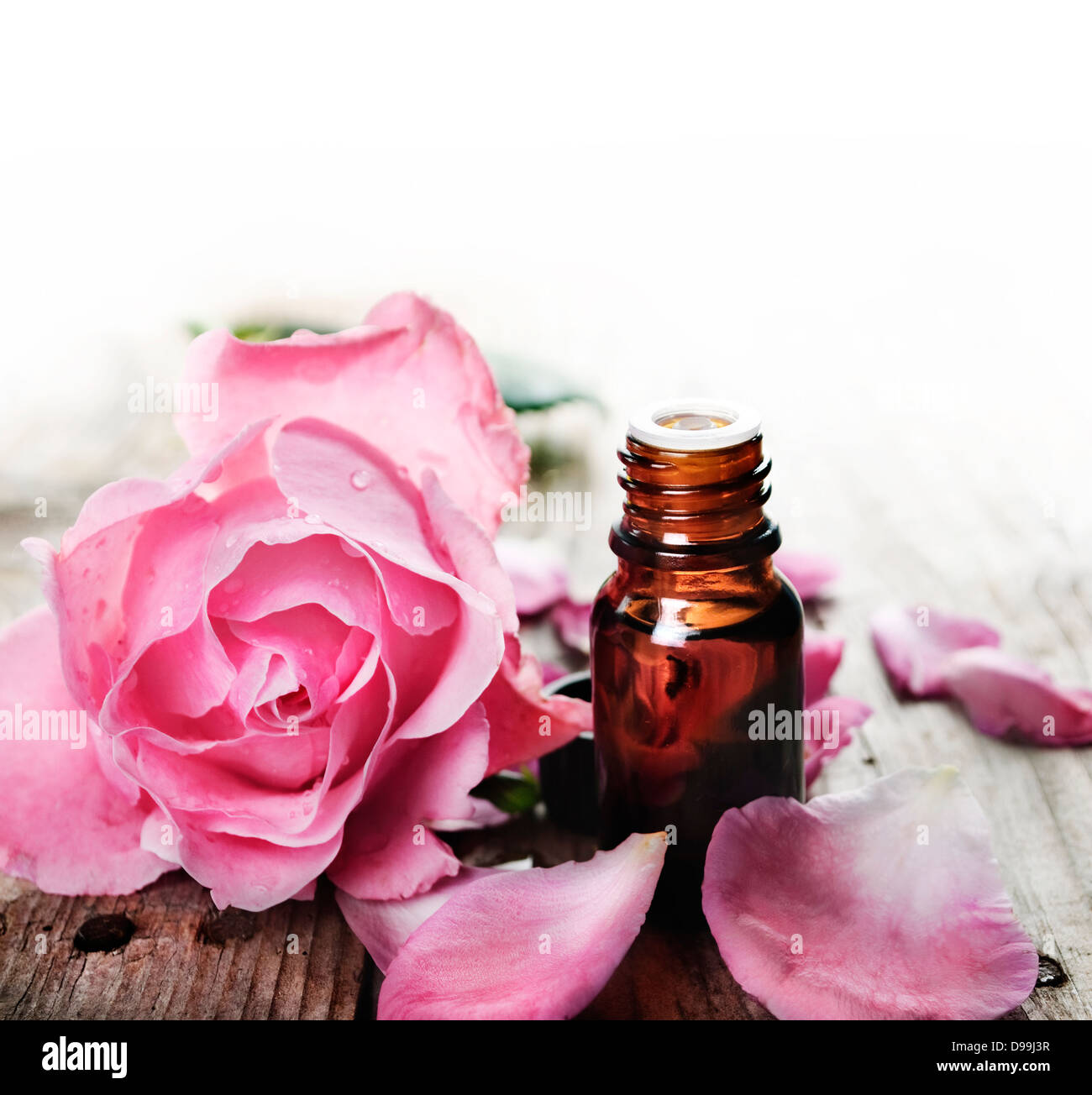 Olio essenziale di petali di rosa su sfondo di legno Foto Stock