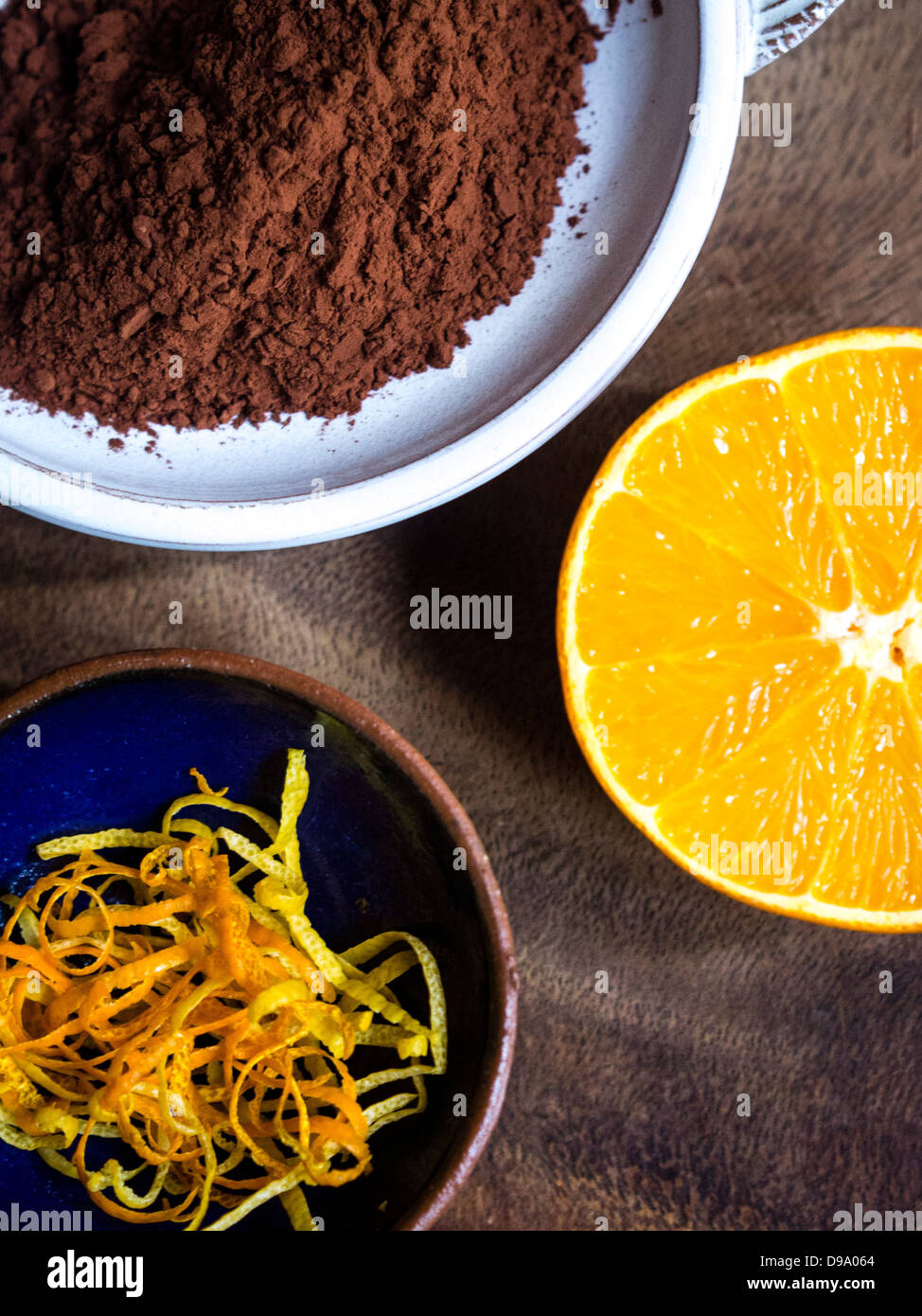 Cacao in polvere, limone e la scorza di arancia strisce, e una mezza arancia che mostra una deliziosa combinazione di sapori Foto Stock