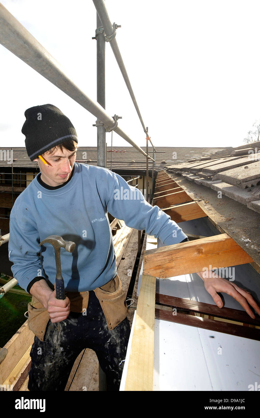 Un copritetti a lavori di riparazione di una perdita sul tetto di una proprietà in una luminosa giornata di sole a Cardiff, nel Galles del Sud. Foto Stock