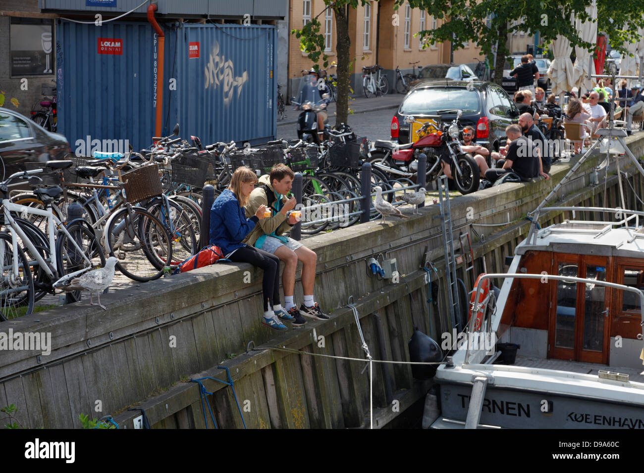 I giovani e gli studenti di godere rinfreschi in ambiente accogliente al sole nel canale Christianshavn, Copenhagen, Danimarca, in un caldo pomeriggio di sabato. Foto Stock