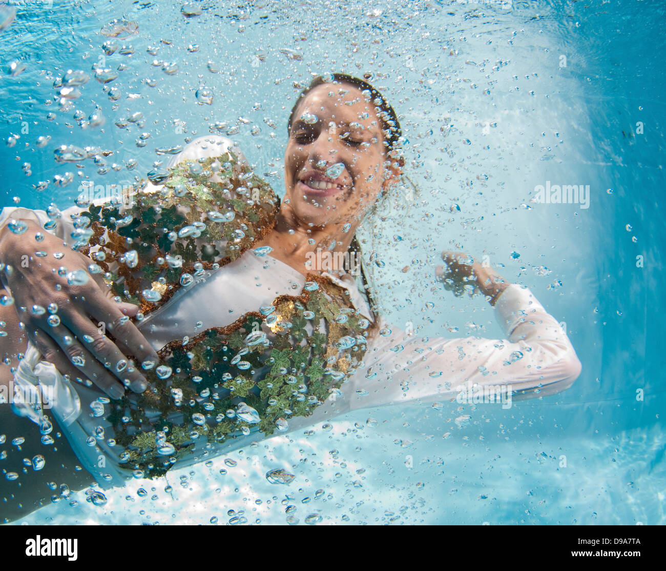 Un giovane vestito alla moda donna galleggia sott'acqua in bolle di aria modello di rilascio disponibili Foto Stock