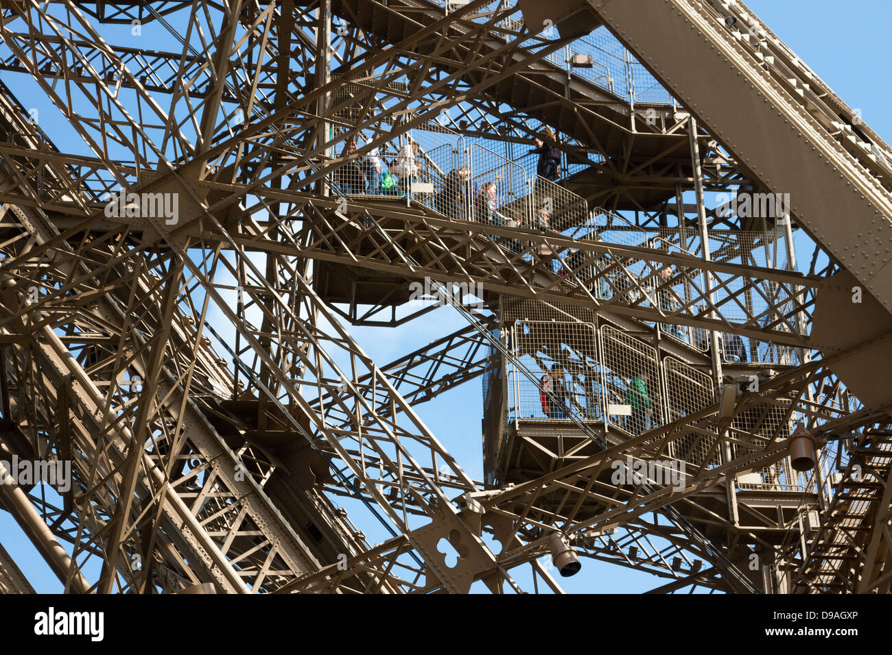 I turisti a piedi verso il basso passi attraverso il complesso reticolo di travi di ferro a scendere dal primo livello della Torre Eiffel a Parigi Foto Stock