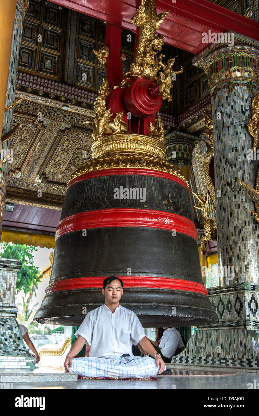 L'uomo meditando da la grande Campana della Dhammazedi Shwedagon pagoda o grande Dagon Pagoda o Golden Pagoda di Yangon MYANMAR Birmania Foto Stock