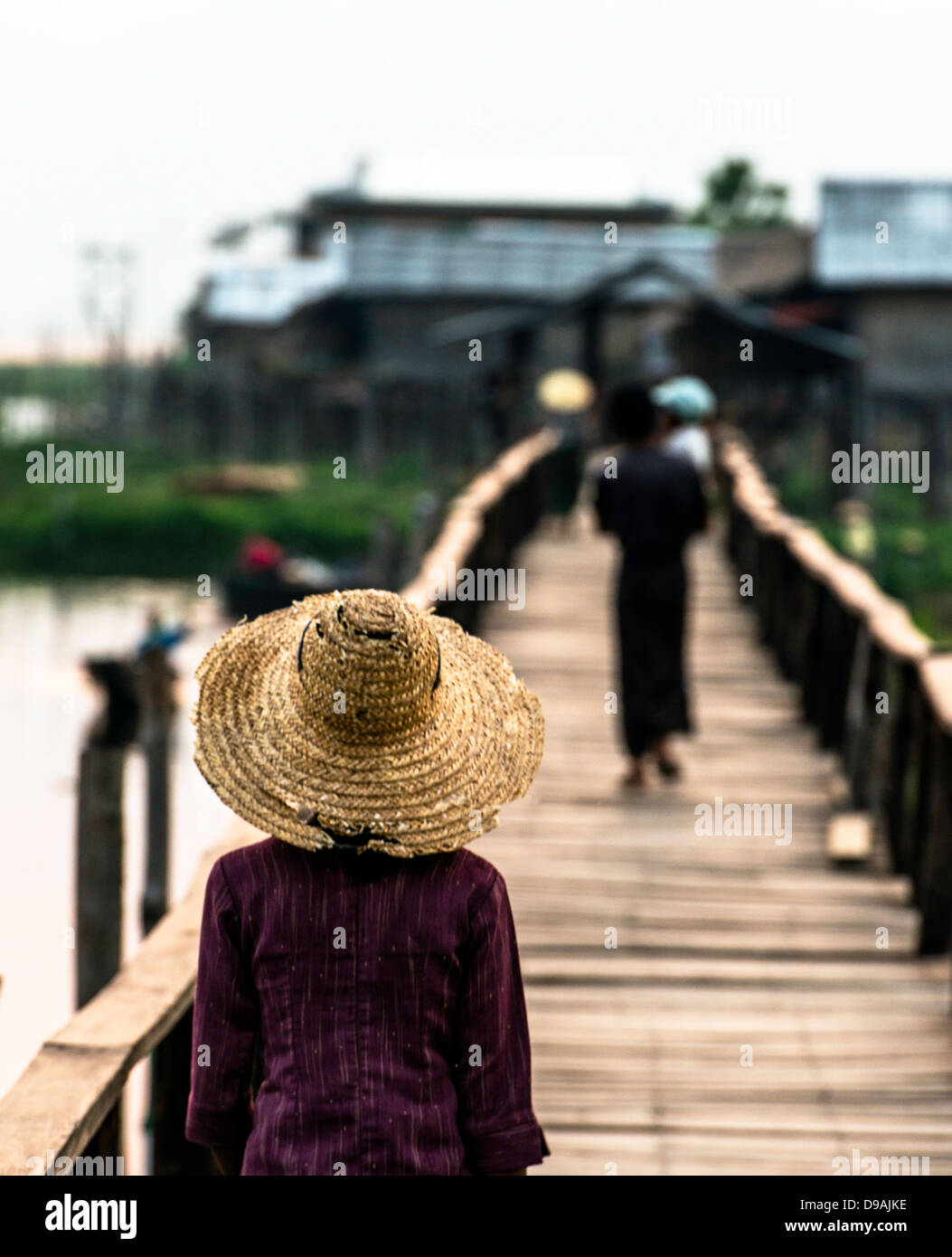 Ragazza birmano attraversando il ponte sul suo ritorno al villaggio Lago Inle MYANMAR Birmania Foto Stock