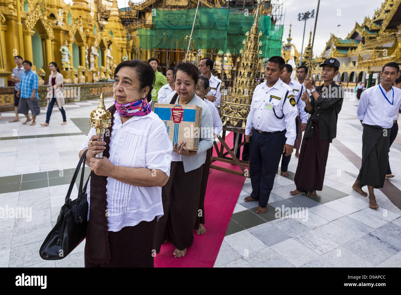 Giugno 15, 2013 - Yangon, Unione di Myanmar - Una donna conduce una famiglia il merito rendendo processione attorno Shwedagon pagoda in Yangon. La Shwedagon pagoda è ufficialmente conosciuta come Shwedagon Zedi Daw ed è anche chiamato la Grande Pagoda di Dagon o la pagoda dorata. Si tratta di un 99 metri (325Â ft) tall pagoda e stupa si trova a Yangon, Birmania. La pagoda si trova ad ovest di Singuttara sulla collina e domina lo skyline della città. È il più sacro pagoda buddista in Myanmar e contiene le reliquie del passato quattro Buddha sancito: il personale di Kakusandha, il filtro dell'acqua di Koá¹‡Ägamana, un pezzo del Foto Stock