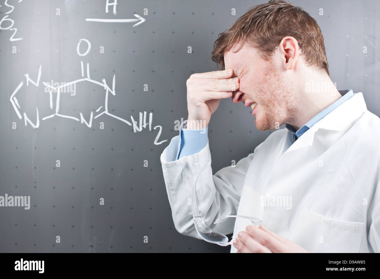 Germania, giovane scienziato con grave espressione facciale e equazione chimica su chalk board Foto Stock