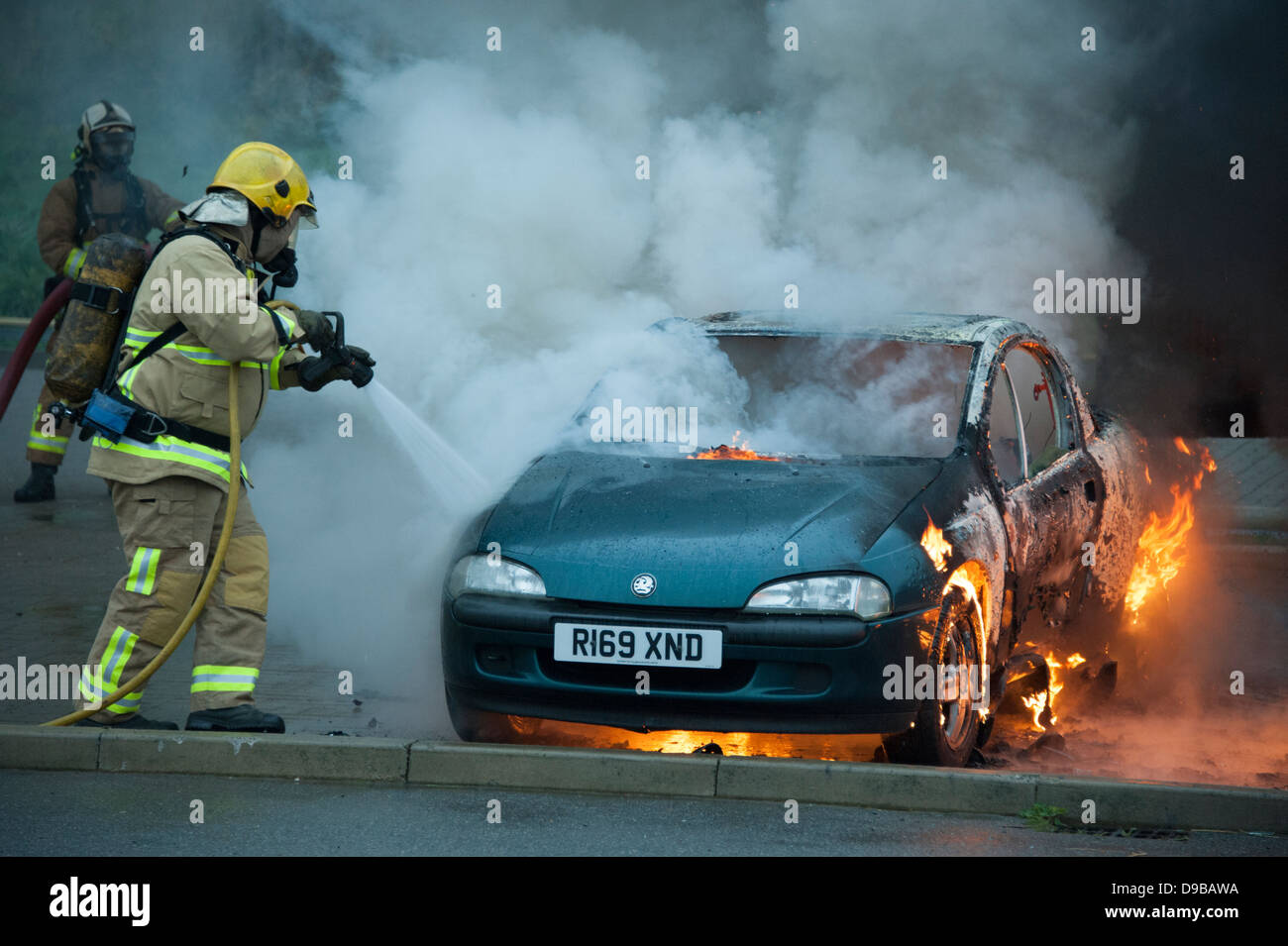 Fireman estinzione incendio sulla vettura benzina bombardato arson fiamme Foto Stock