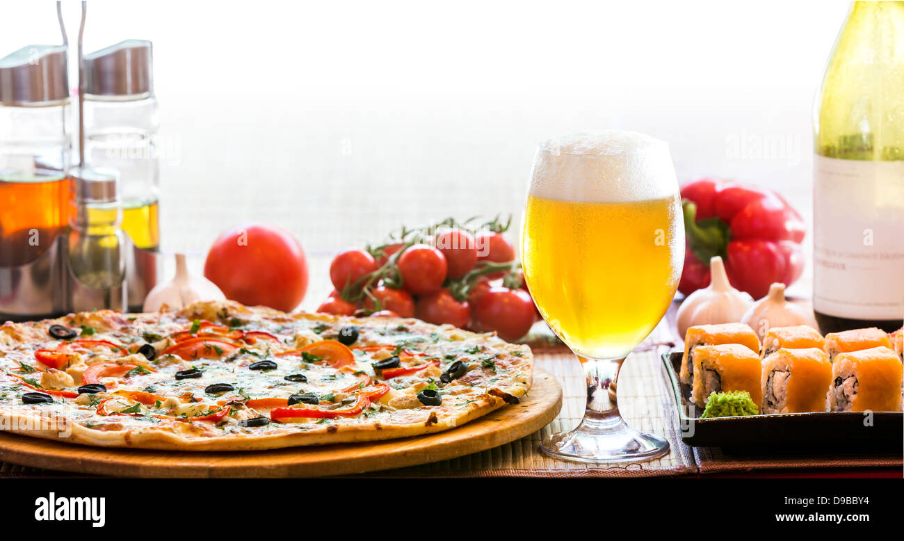 Composizione della birra il sushi e la pizza in retroilluminato Foto Stock