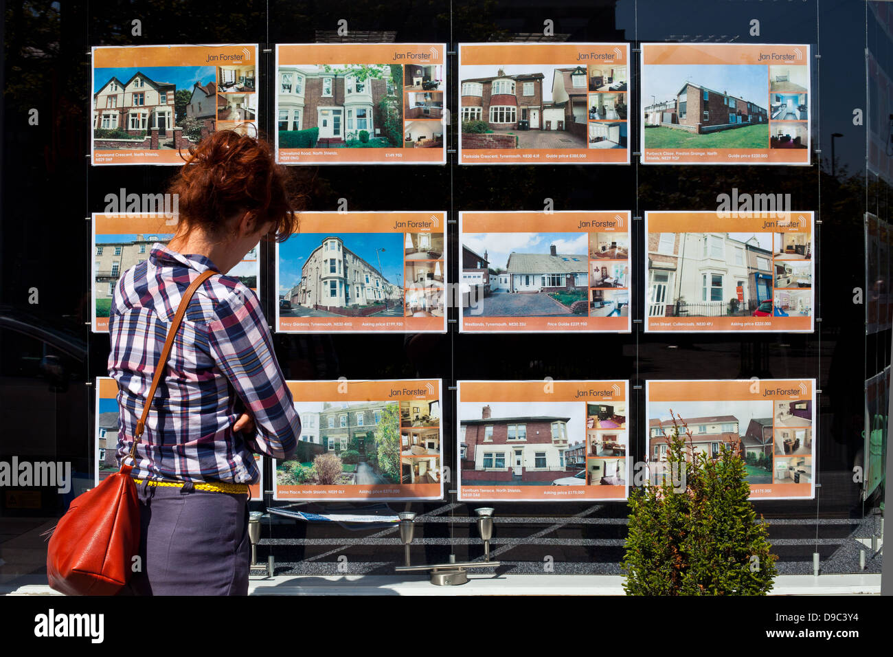 Donna che guarda in agenti immobiliari finestra Foto Stock