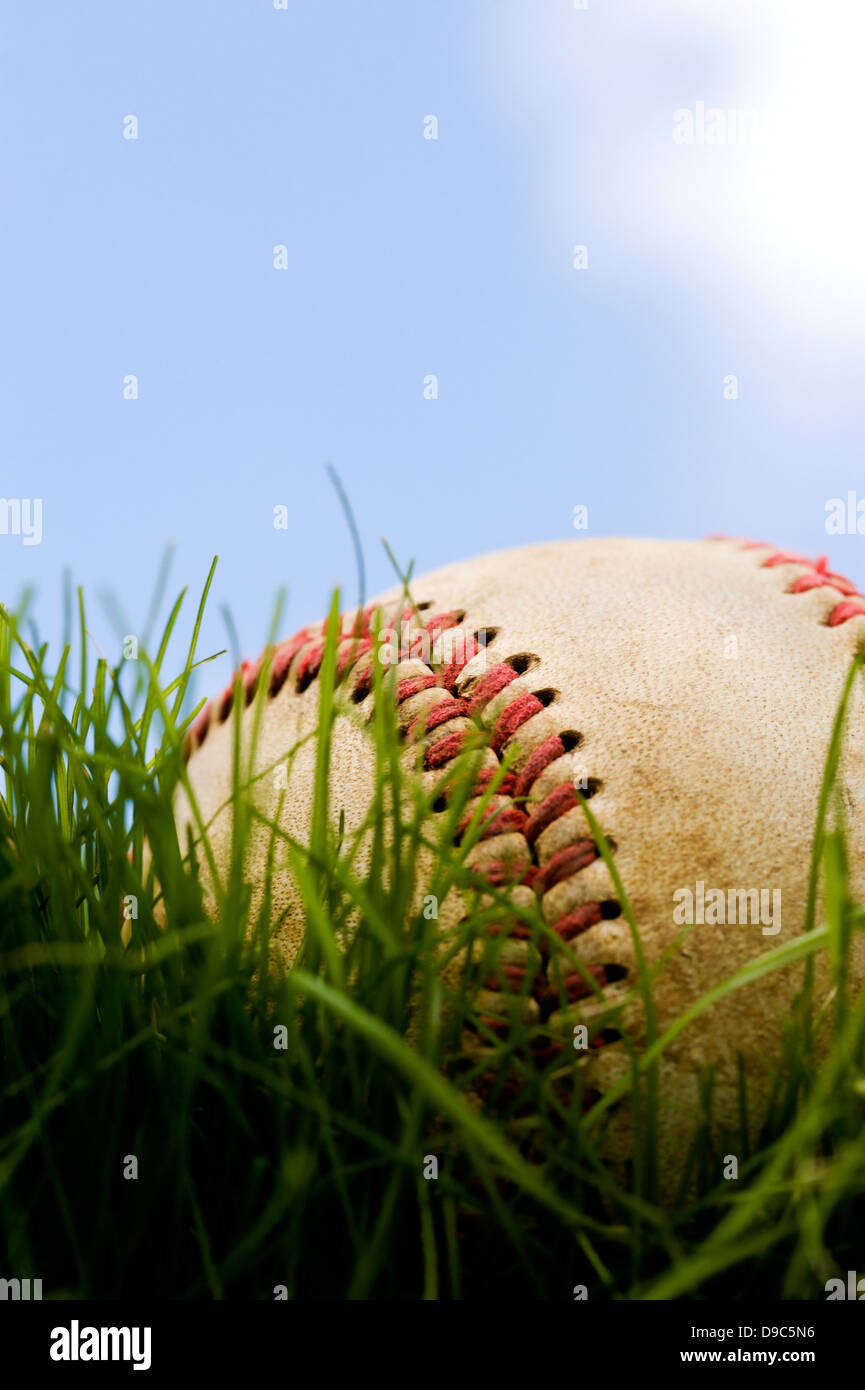 Close-up di un baseball giacente in erba contro un poco nuvoloso sky Foto Stock