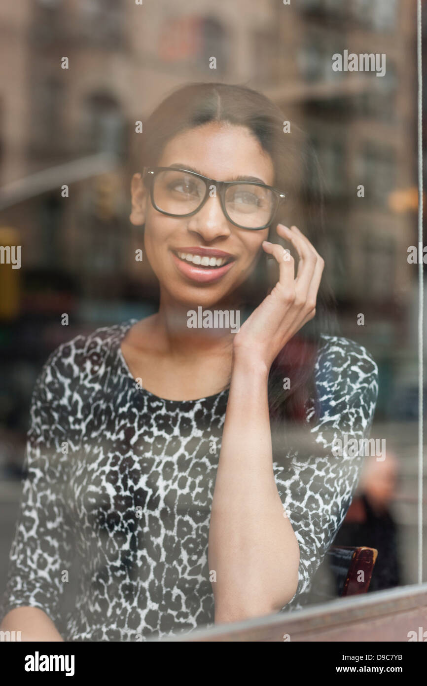 Donna che guarda fuori della finestra parlando al cellulare Foto Stock