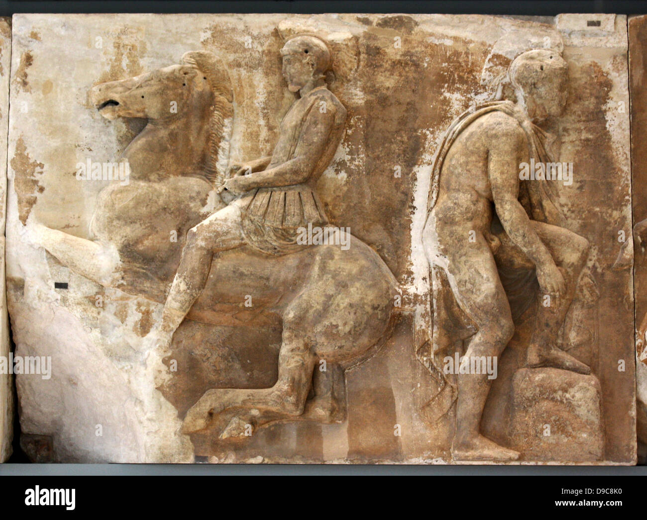 Un cavaliere galoppa verso destra. Egli è vestito come un oplita con una corazza anatomica con lembi realizzati in pelle, a forma di leone spalline e un gorgoneion presso lo sterno. Dietro di lui è una gioventù che indossa un capo. Egli è rivolta in direzione opposta e si piega verso il basso per fissare il sandalo sul suo piede sinistro, che si appoggia su una roccia. Foto Stock