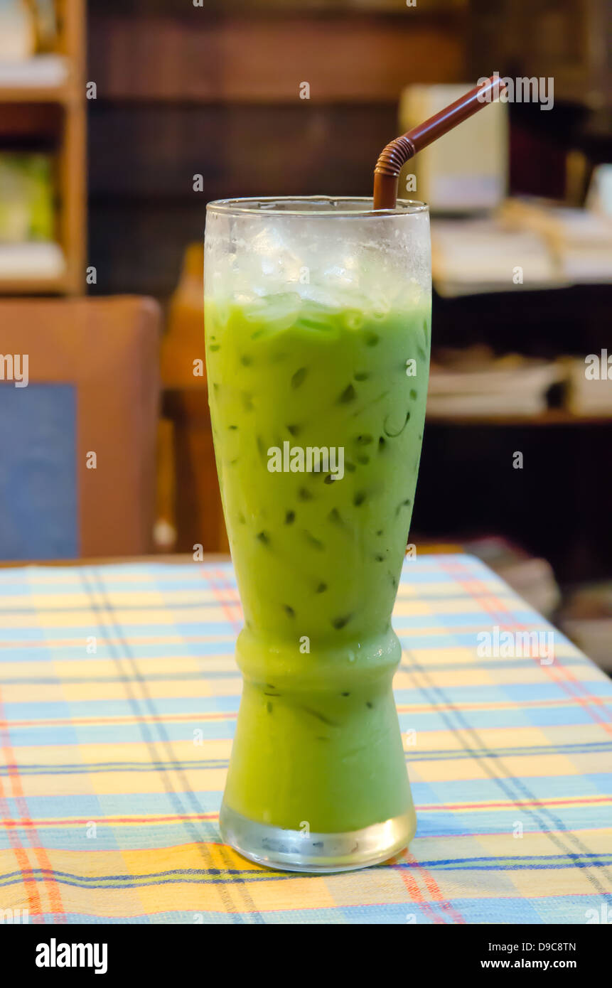 Latte ghiacciato tè verde con paglia sul tavolo Foto Stock