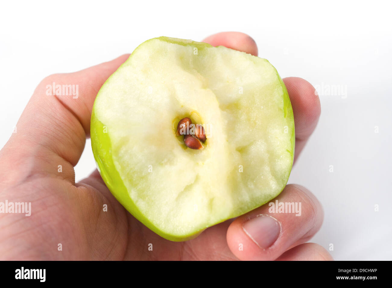 Tenendo premuto a metà mangiato mela verde che mostra il nucleo e semi Foto Stock