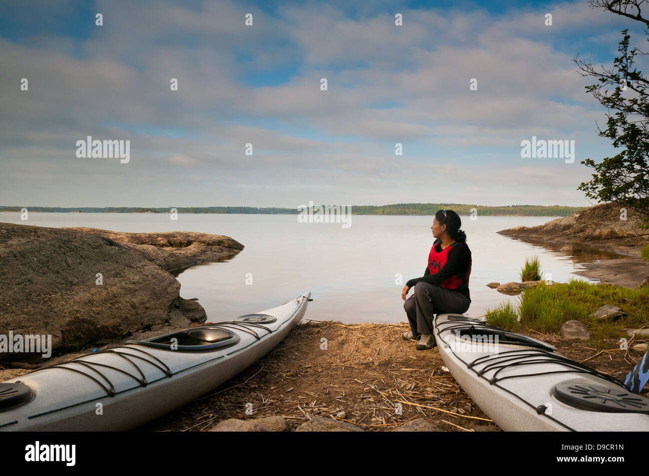 Kayak paddler seduto su un kayak presso il lungolago di Vansjø in Østfold, Norvegia. Vansjø è una parte dell'acqua sistema chiamato Morsavassdraget. Foto Stock