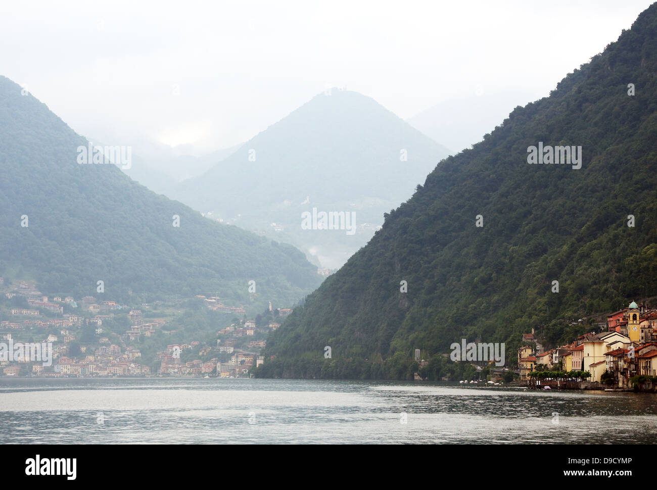 Le montagne si elevano al di sopra di villaggi lungo le rive del lago di Como in Italia settentrionale Foto Stock