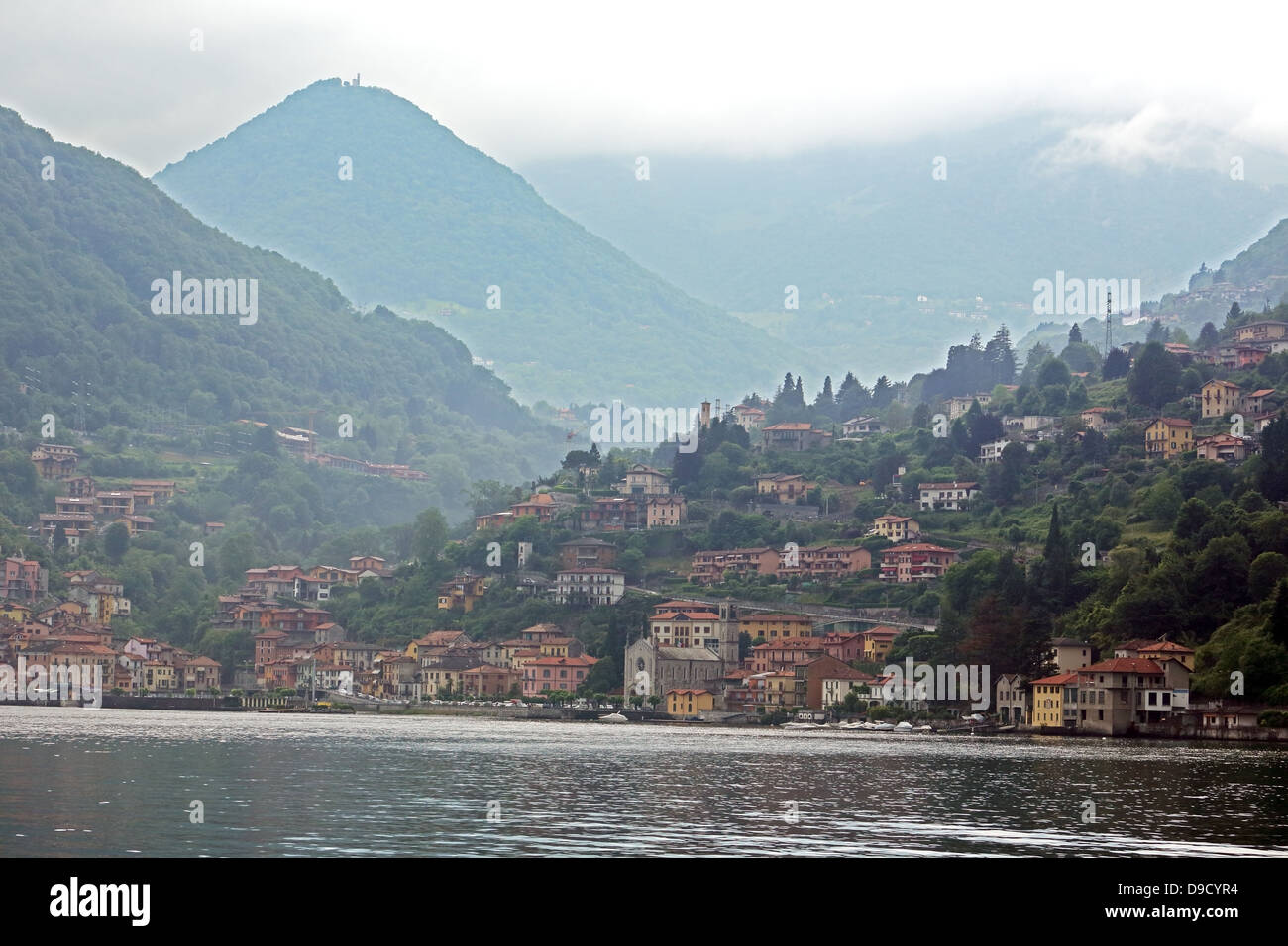 Le montagne si elevano al di sopra di villaggi lungo le rive del lago di Como in Italia settentrionale Foto Stock