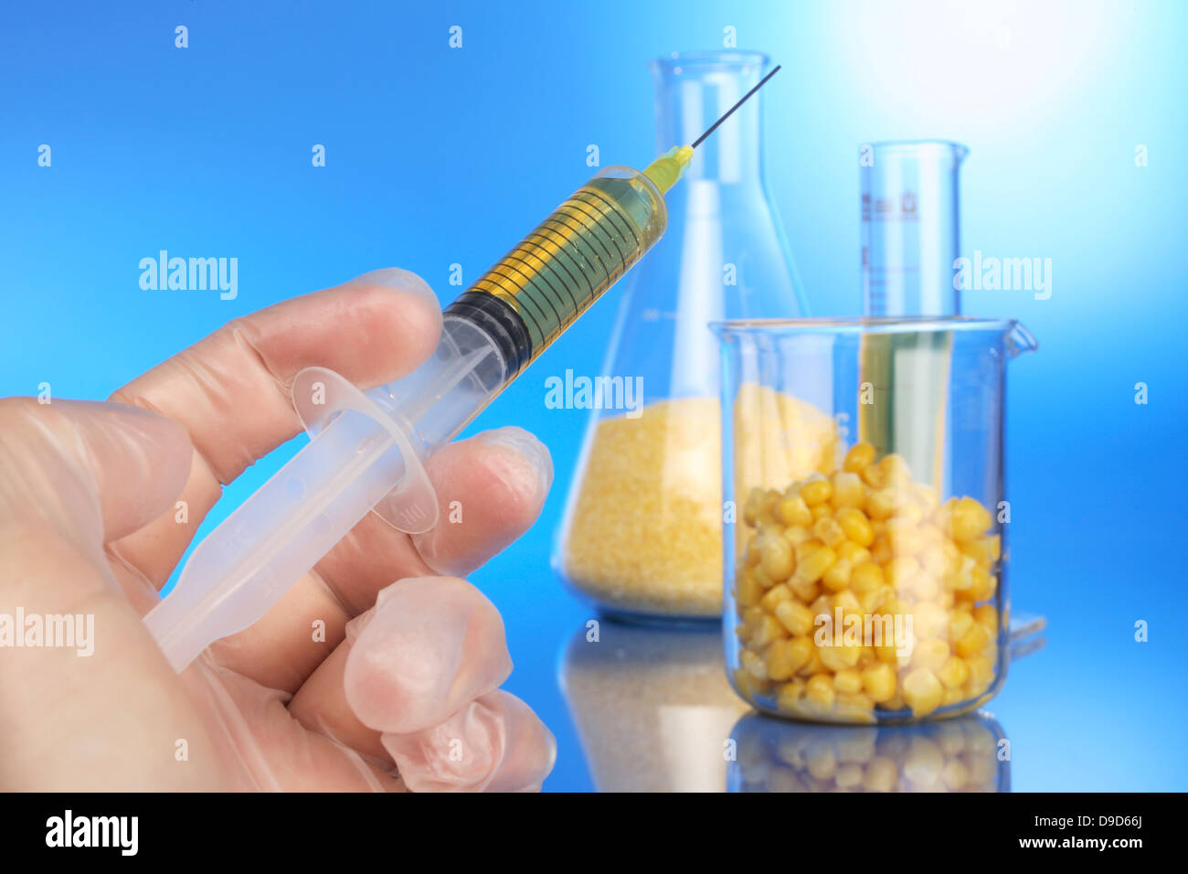Mano con la siringa e la tazza di misura con il mais Foto Stock