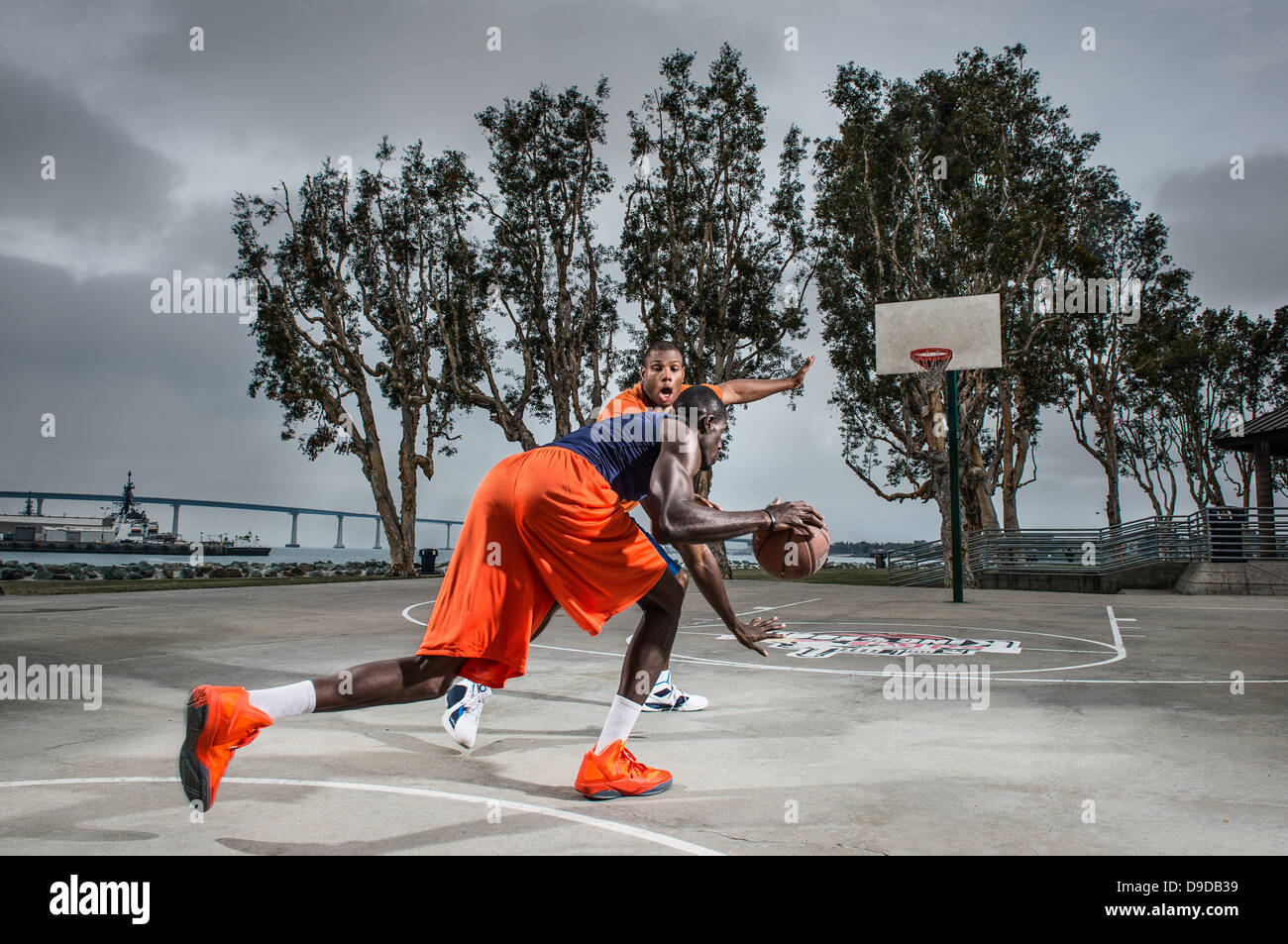 Giovani uomini giocare a basket su corte Foto Stock