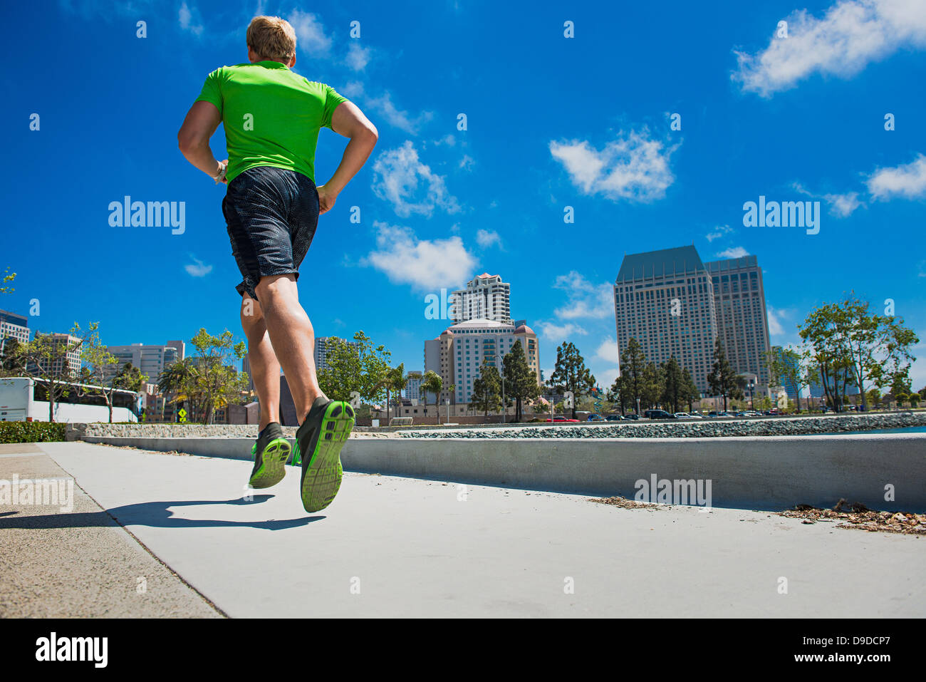 Giovane uomo jogging in città, vista posteriore Foto Stock