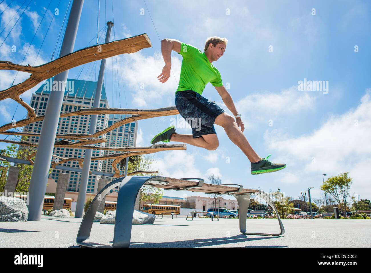 Giovane uomo che saltava su una panchina nel parco in città Foto Stock
