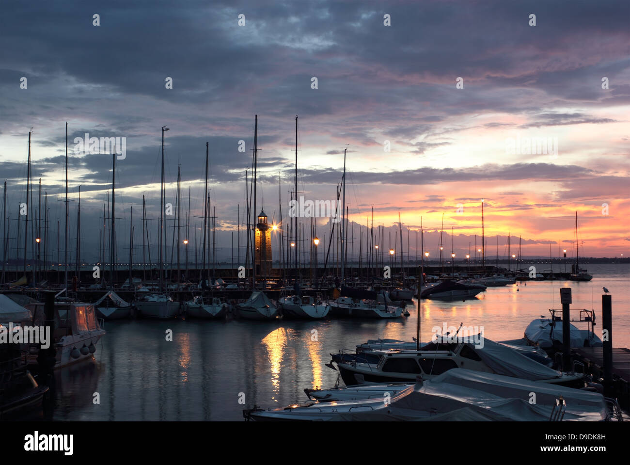 Sunrise colorato a Desenzano del Garda con il porto turistico e il vecchio faro. Foto Stock
