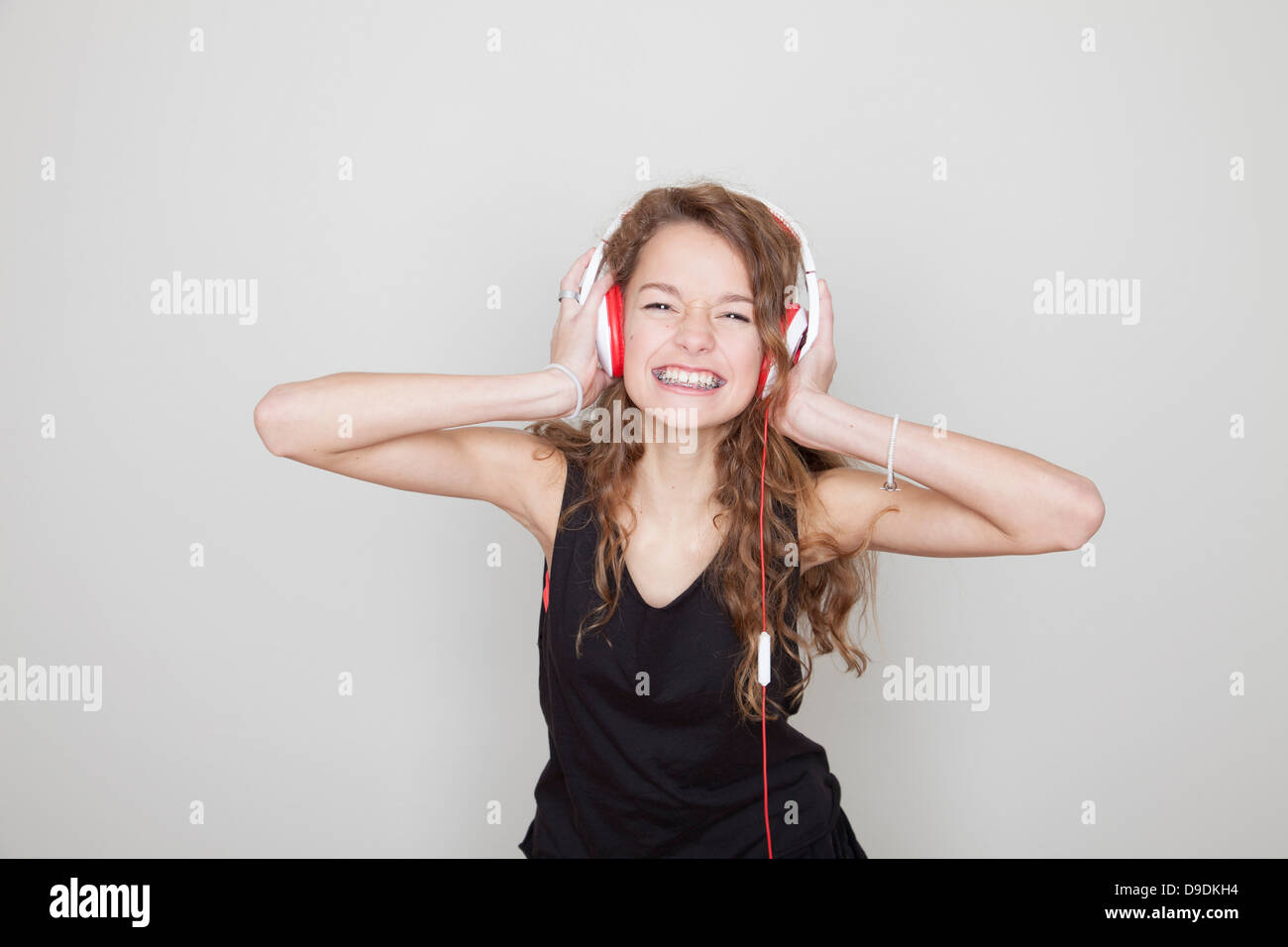 Ragazza che indossa le cuffie con le mani sulle orecchie Foto Stock