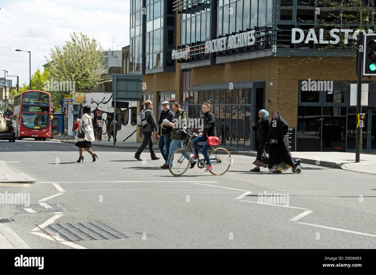 Persone e il ciclista attraversando la strada, Dalston Junction, London Borough of Hackney, England, Regno Unito Foto Stock