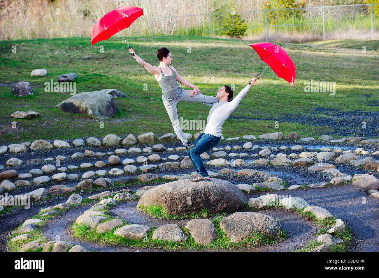 Metà adulto ballerini eseguono con red ombrelloni nel cerchio di pietra Foto Stock