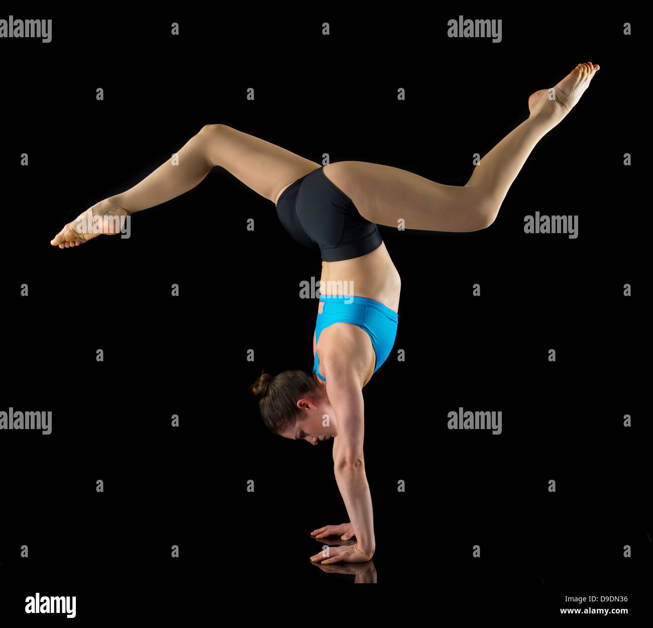 Acrobat esegue handstand davanti a sfondo nero Foto Stock