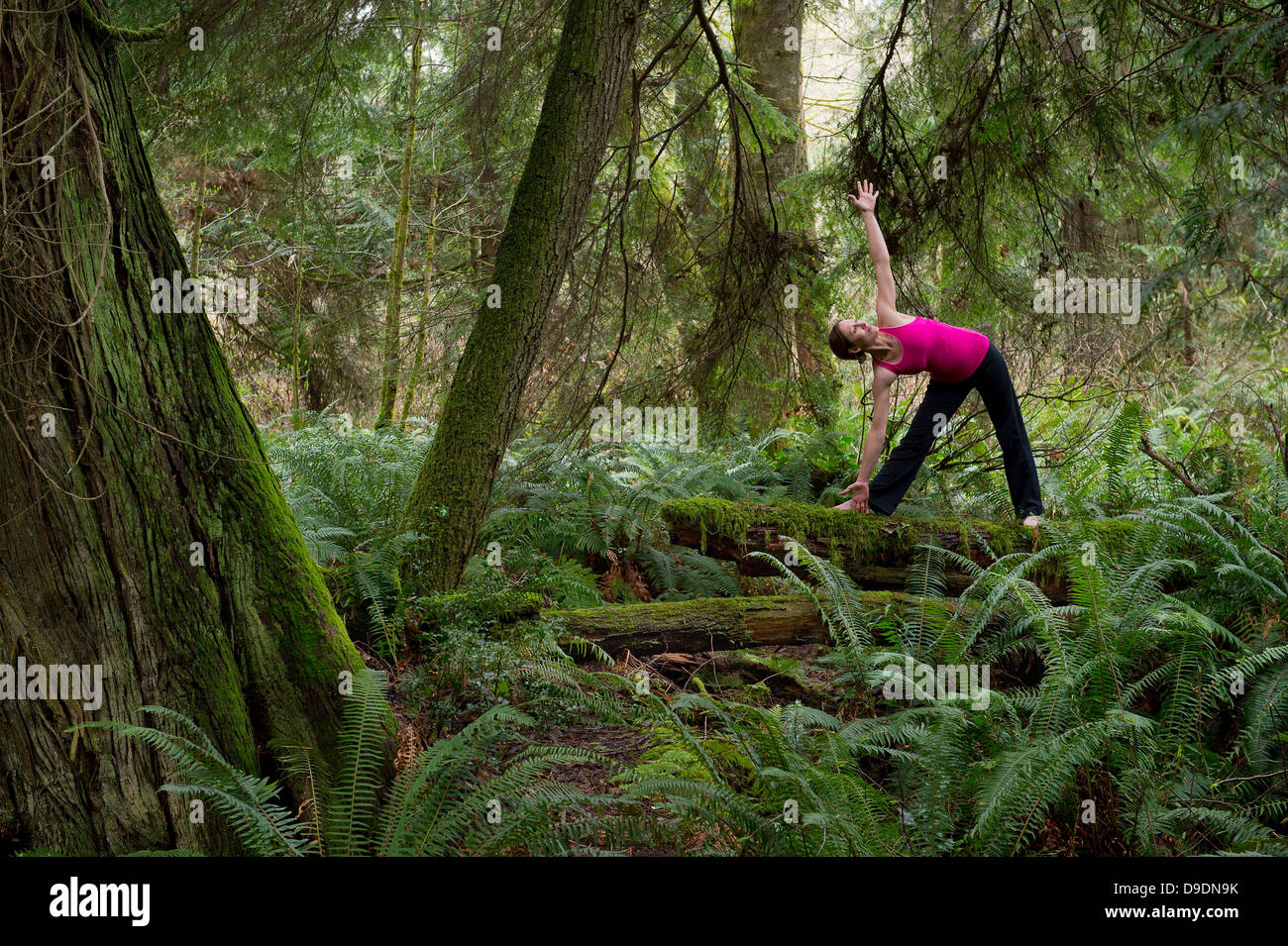 Donna matura di eseguire la posa di triangolo in foresta Foto Stock