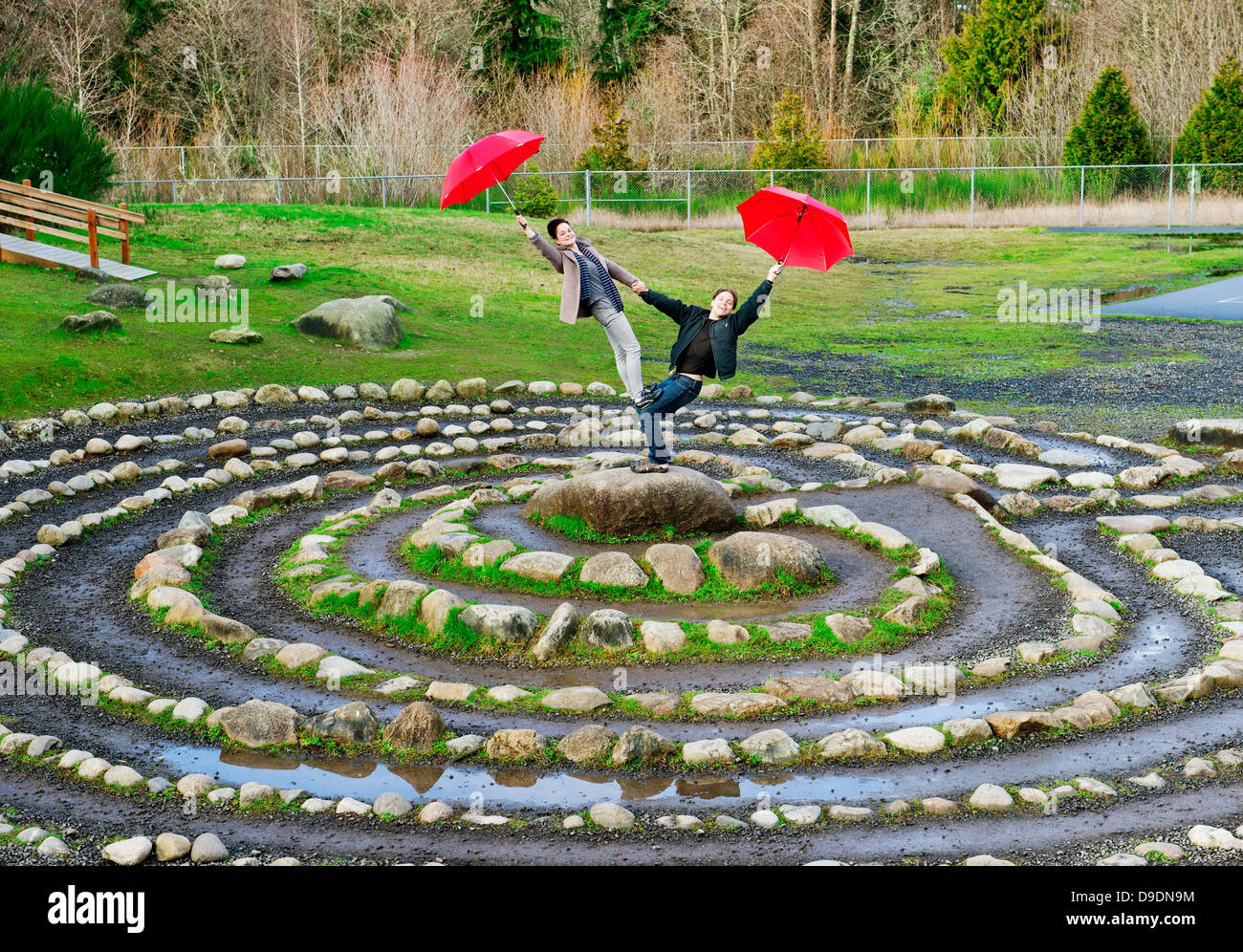Metà adulto ballerini eseguono con red ombrelloni nel cerchio di pietra Foto Stock