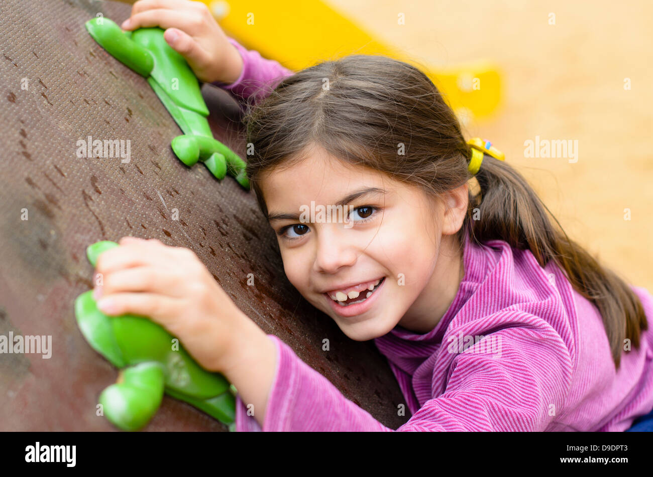 Bambina su una parete di arrampicata in un parco Foto Stock