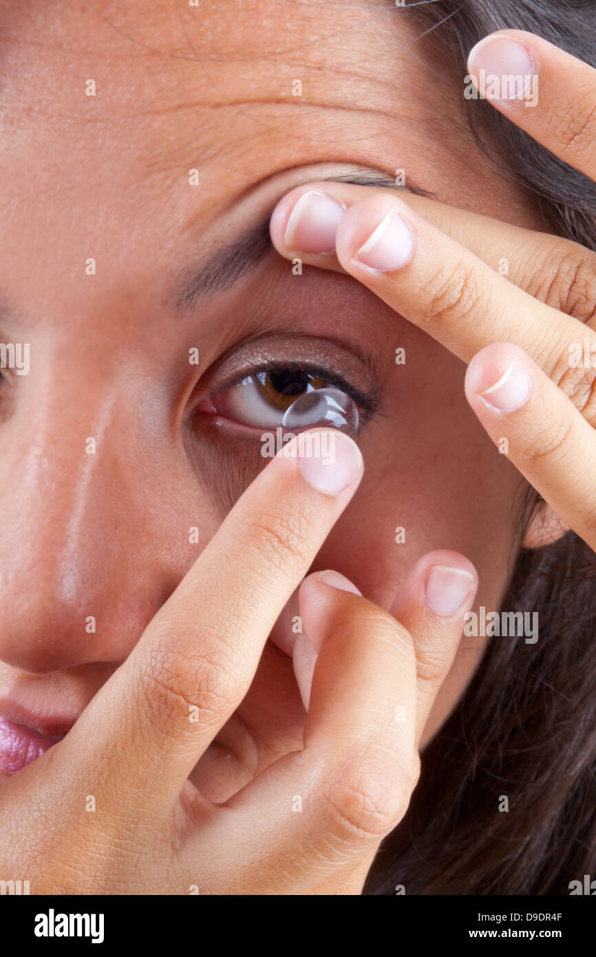 Vista di una donna occhio marrone durante l'inserimento di una lente a contatto Foto Stock
